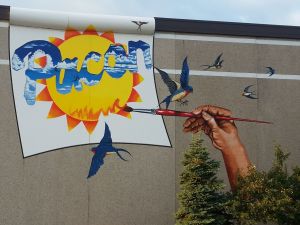 Colorful mural featuring a hand painting a sun and flying birds.