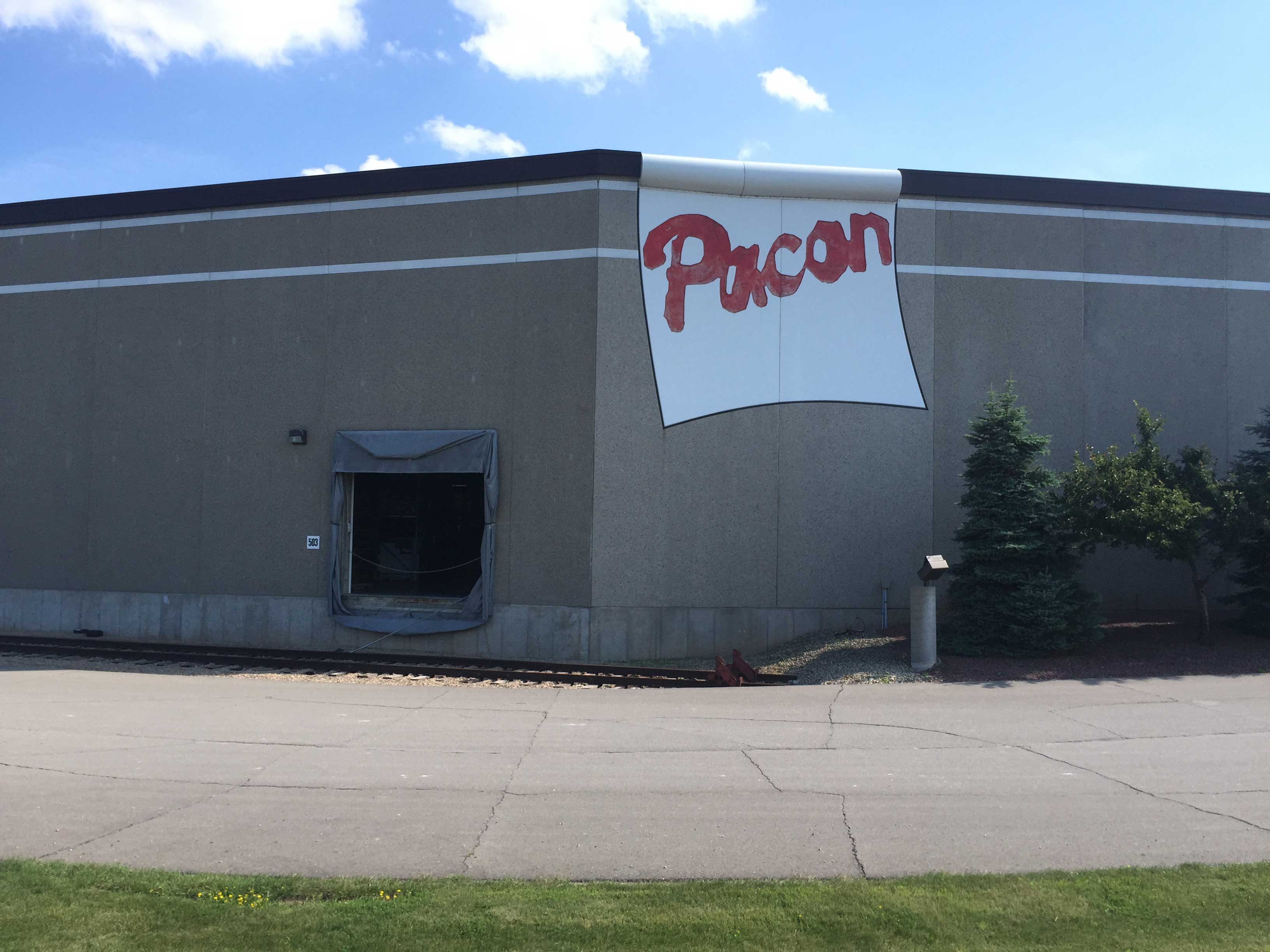 Pacon building exterior with large sign and loading dock area.